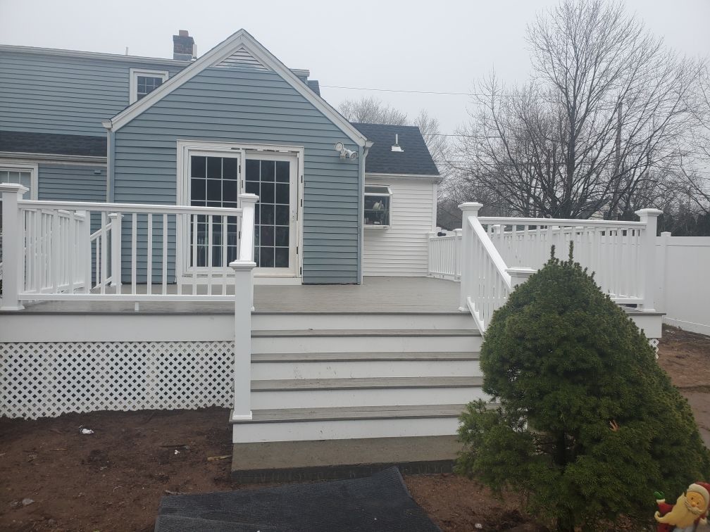 Back of blue house with white deck, steps, and railing.