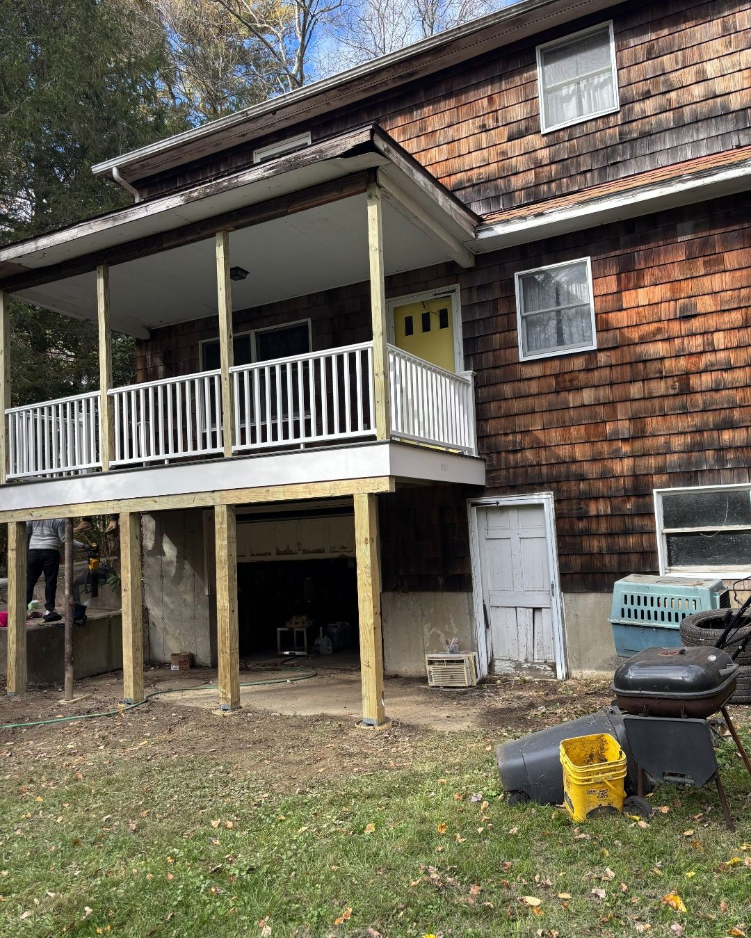 Two-story house with newly constructed porch. Brown siding and shingled roof. White railing and posts.