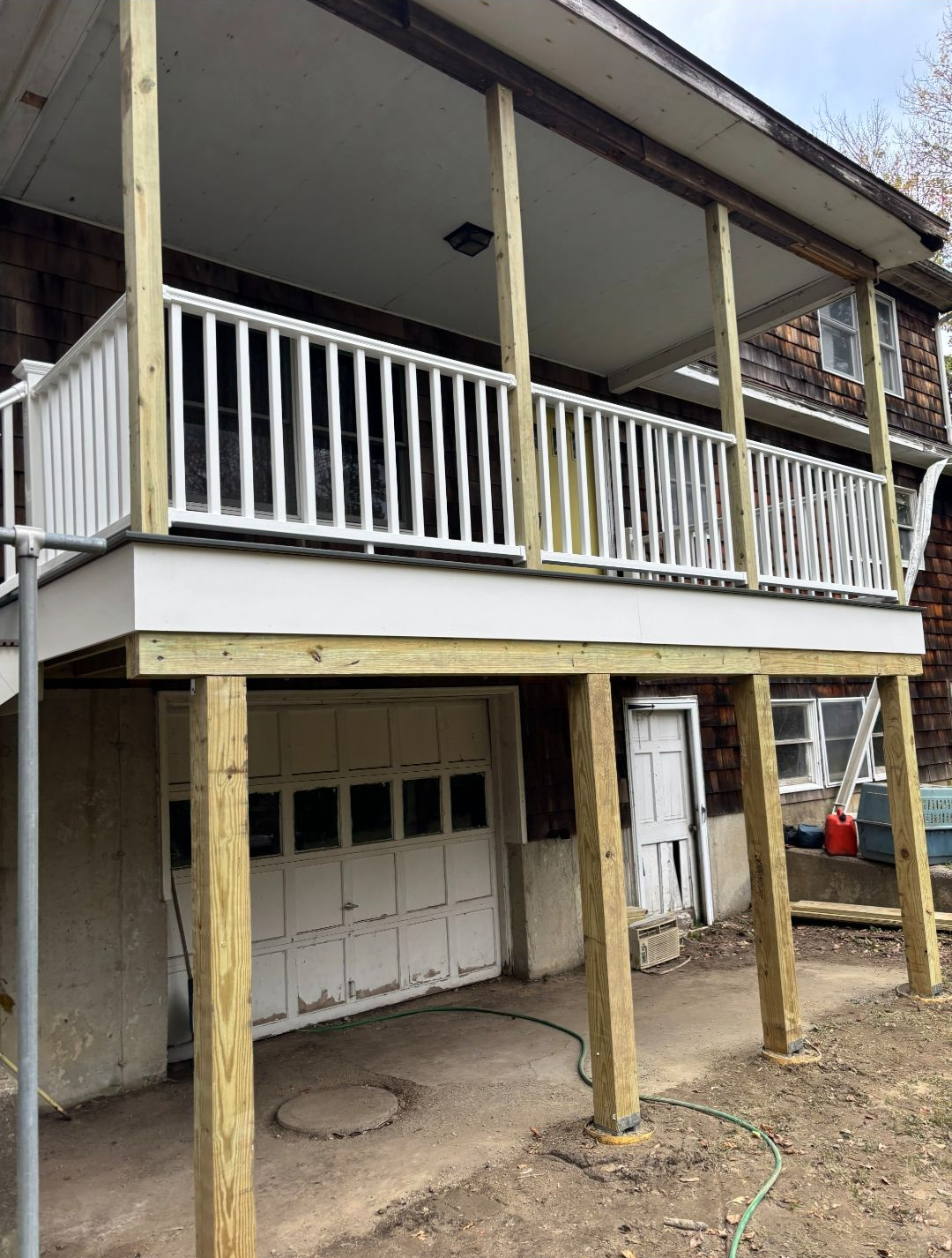 Deck with white railing and support posts over a garage.