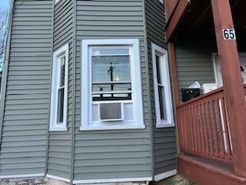 Gray house with bay windows and a porch, number 65.