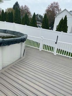 Deck with above-ground pool, white fence, and greenery. Overcast day.
