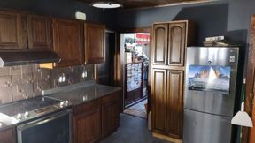 Kitchen with dark wood cabinets, stainless steel appliances, and a hallway in the background.