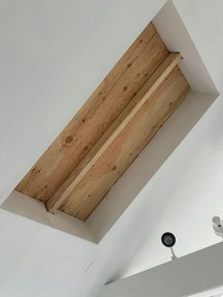 Ceiling opening with exposed wooden beams, surrounded by white painted trim.