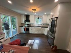 Kitchen with white cabinets, dark countertops, stainless steel appliances, and a person in doorway.