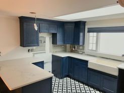 Navy blue kitchen cabinets and white countertops with a patterned tile floor.