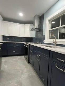 Modern kitchen with two-tone blue and white cabinets, stainless steel appliances, and a light blue backsplash.