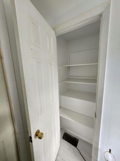 White closet with several shelves and a partially open white door.