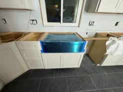 Kitchen cabinetry installation, featuring a sink with blue protective film, unfinished countertop.