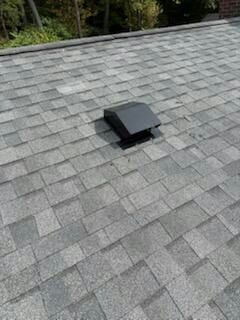 Gray asphalt shingle roof with a black rectangular vent.