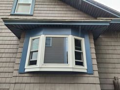 Bay window painted blue on a house with gray siding.