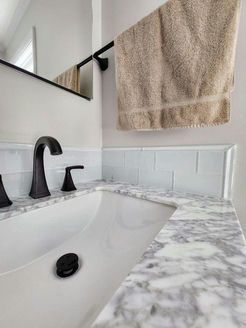 White bathroom sink with marble countertop and black faucet; a towel hangs nearby.