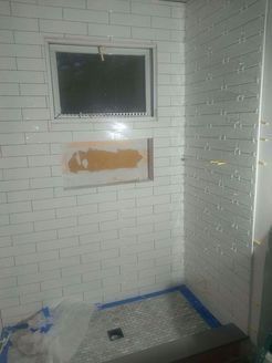Bathroom with white subway tile, window, and shower floor.