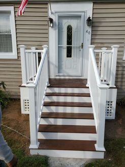 White-railed steps leading to a front door with a glass panel. Brown and white exterior.