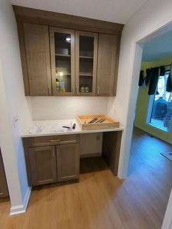 Built-in kitchen storage unit: upper cabinets with glass doors, countertop with desk space, lower cabinets, neutral colors.