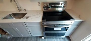 Kitchen countertop with a stainless steel stove and sink with cabinets below.