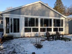 Sunroom addition with large windows and snow-covered ground; two chairs on the patio.