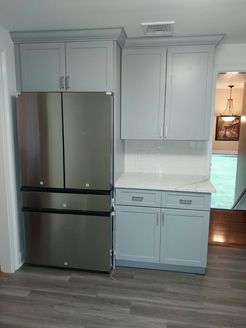 Stainless steel refrigerator and light blue cabinets in a kitchen.