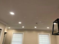Cream-colored ceiling with recessed lights, crown molding, and two windows with white blinds, viewed from below.