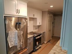 A small kitchen with stainless steel appliances, white cabinets, and a gray countertop.