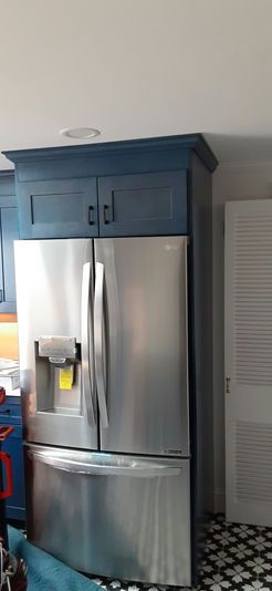 Stainless steel refrigerator with blue cabinets in a kitchen.