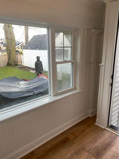 Interior room with window overlooking backyard, white paneling, wooden floor, and a closet.