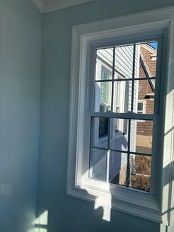 Window with white trim and a grid, inside a room with light blue walls.