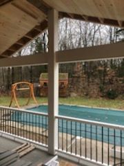Covered porch with view of backyard, pool, and swing set.