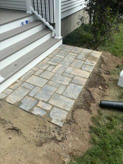 Stone pavers leading from wooden porch stairs to a grassy yard.