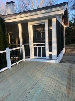 Screened porch with white trim, black screens, and wooden deck in natural light.