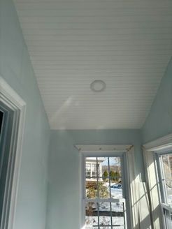 Light blue walls and a white paneled ceiling in a room with a window.