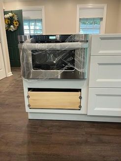 Built-in microwave oven installed in white kitchen cabinetry. A drawer is below it.