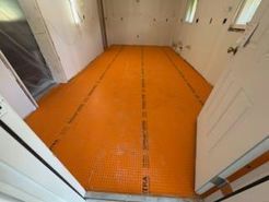 Orange flooring laid in a room with white walls, possibly for tiling.