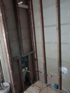 Bathroom wall studs and plumbing pipes exposed during renovation.