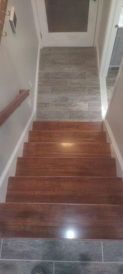 Wooden staircase with brown steps and gray tiled landing. White trim.