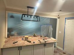 Kitchen island with white cabinets, tools, and a black light fixture, undergoing renovation.