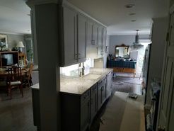 Gray kitchen cabinets and countertop with a sink and a view of the dining area.
