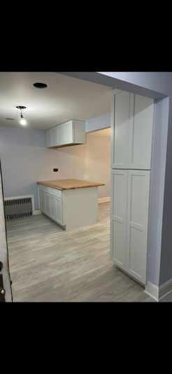 A light-colored kitchen with an island, cabinets, and wood countertops.