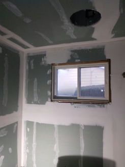 Interior room under construction, with drywall and a window.