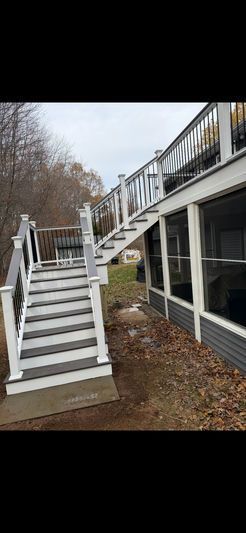 Exterior view of a deck with stairs and a screened porch. The stairs are painted white with gray steps.