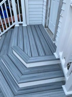 Gray composite deck with white trim and railing; door visible in background.