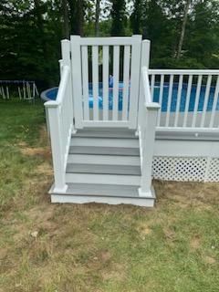 White gate and stairs leading to a swimming pool with a white fence.
