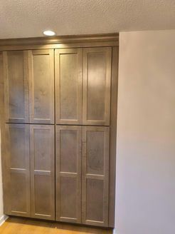 Gray wooden pantry cabinets built into a wall.