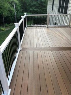 Wooden deck with white railings, black balusters, overlooking a grassy yard.