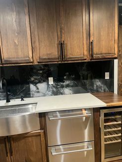 Kitchen with dark wood cabinets, black and white backsplash, stainless steel appliances, and white countertop.