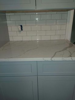 Light blue kitchen cabinets with white countertops and subway tile backsplash.