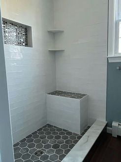 Bathroom with white tiled walls, gray hexagon floor, and built-in bench.