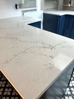 White countertop with gray veining on blue kitchen cabinets.