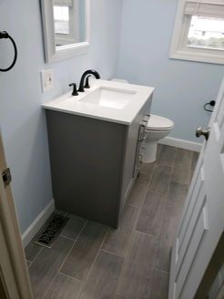 Small bathroom with gray vanity, white sink, and light blue walls.