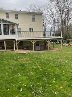 Two-story house with a wooden deck overlooking a grassy backyard.