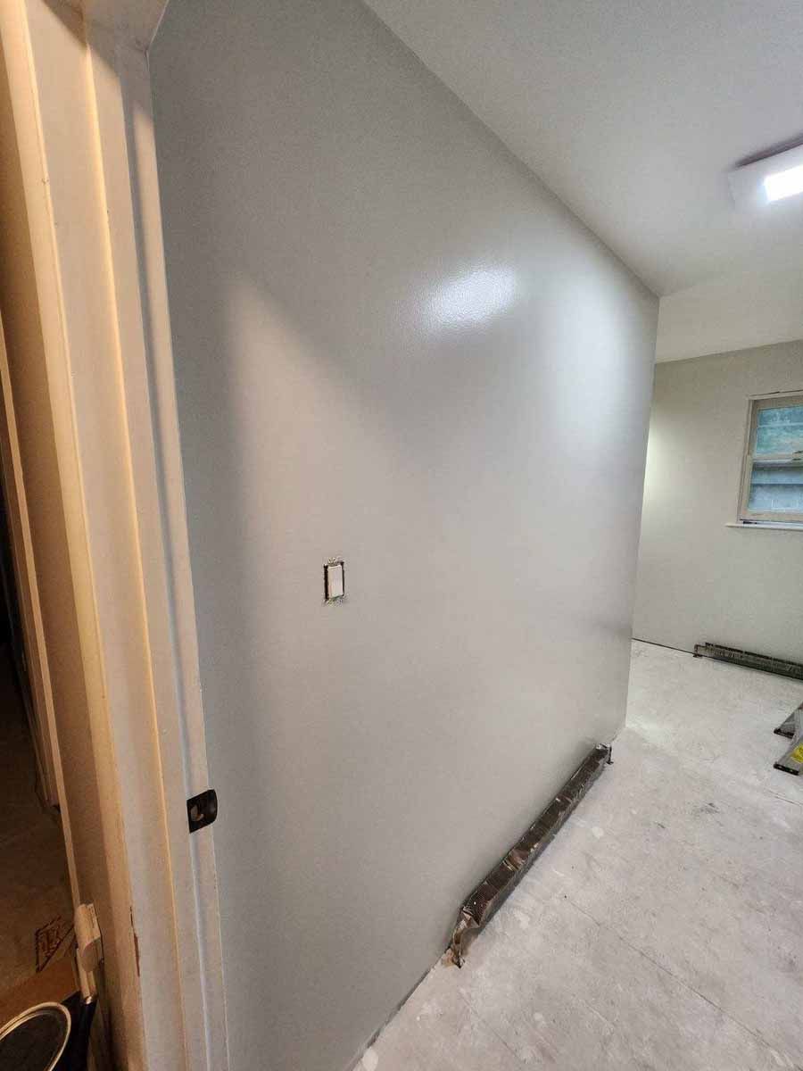 Light gray painted interior wall with light switch, doorway, and window, possibly under construction.